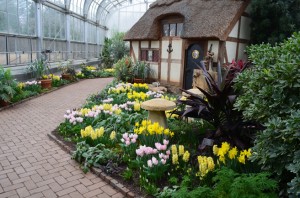 A cottage with tulips and daffodils in front.